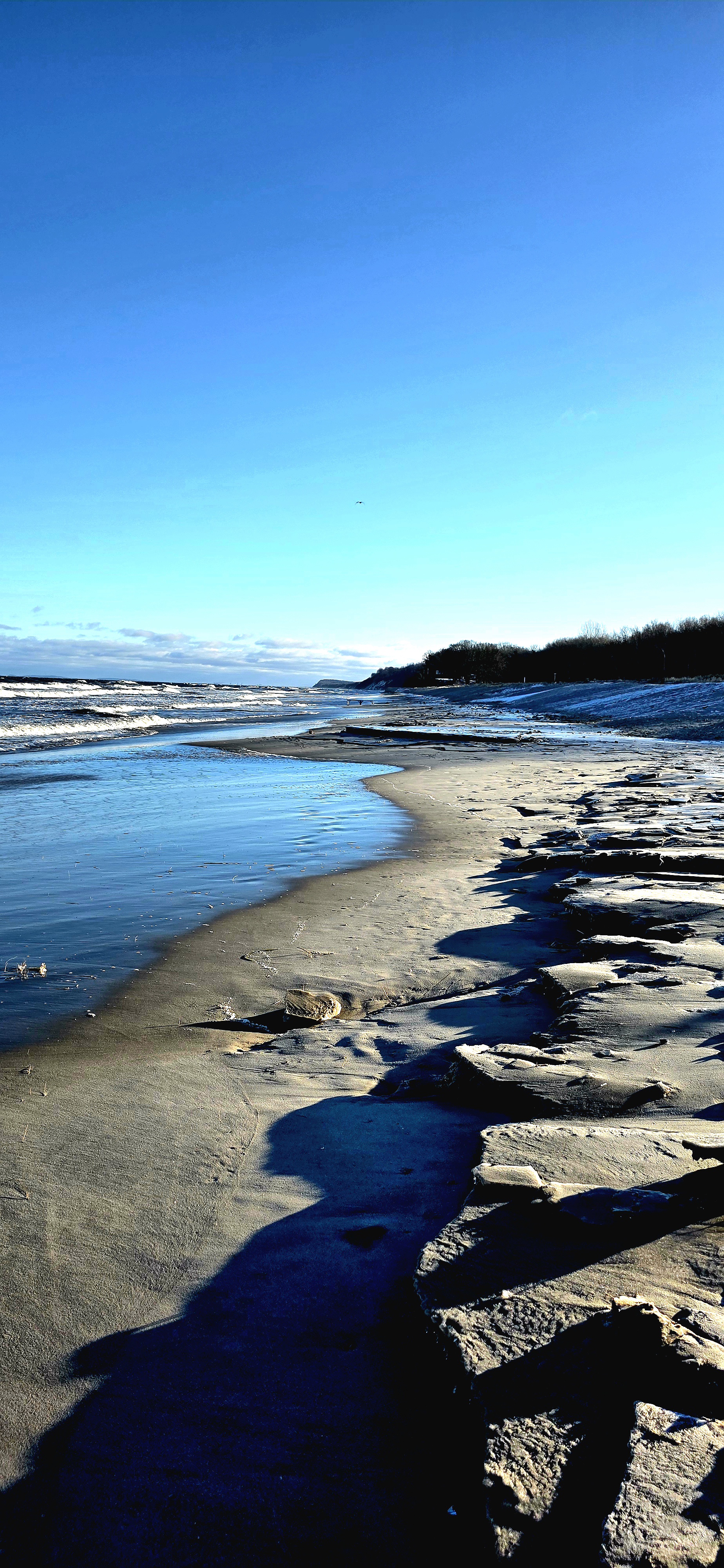 Winterstrand in Kölpinsee mit Eisplatten am Ufer und Blick entlang der Ostsee