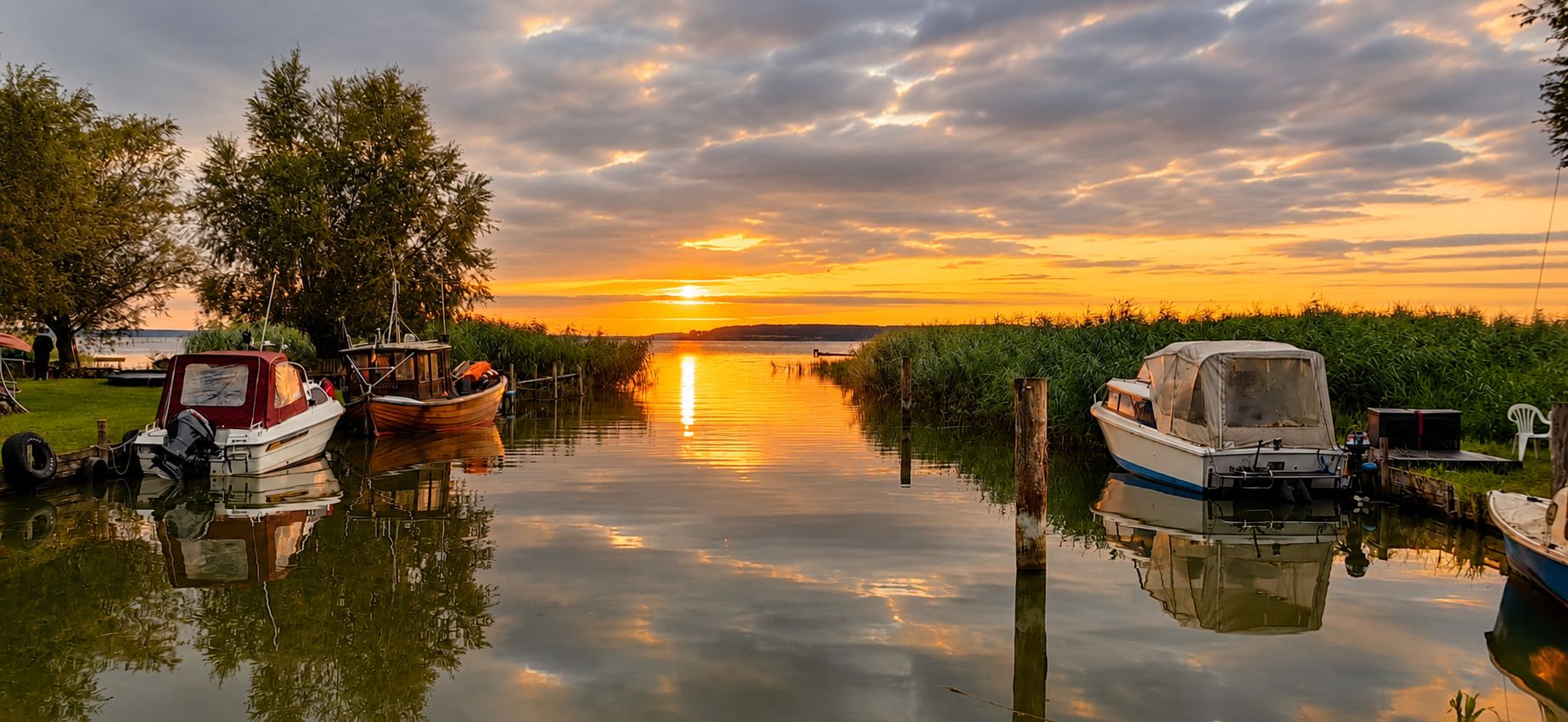 Sonnenuntergang am Achterwasser in Warthe im Lieper Winkel mit Booten und ruhigem Wasser